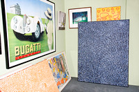 A framed Bugatti poster and aboriginal paintings in the workshop